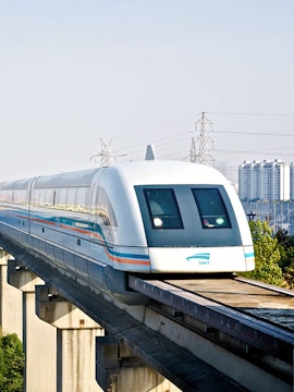 Shanghai Maglev Train traveling on elevated track with cityscape in background.