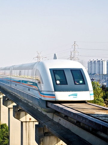 Shanghai Maglev Train traveling on elevated track with cityscape in background.
