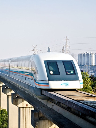 Shanghai Maglev Train traveling on elevated track with cityscape in background.