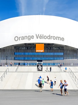 Visitors walking towards the entrance of Orange Vélodrome stadium in Marseille, France.