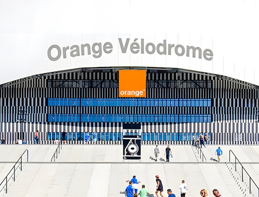 Visitors walking towards the entrance of Orange Vélodrome stadium in Marseille, France.