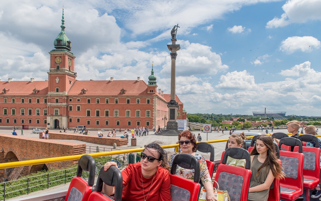 Open-top bus tour passing Warsaw's Royal Castle and Sigismund's Column.