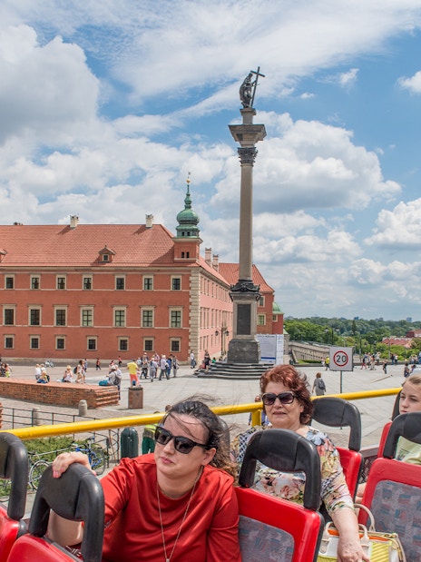 Open-top bus tour passing Warsaw's Royal Castle and Sigismund's Column.