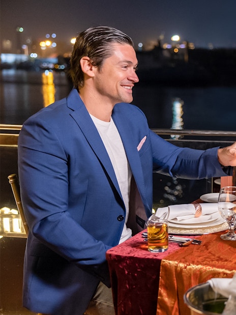 Couple toasting on Dubai Canal cruise at night with city lights in background.
