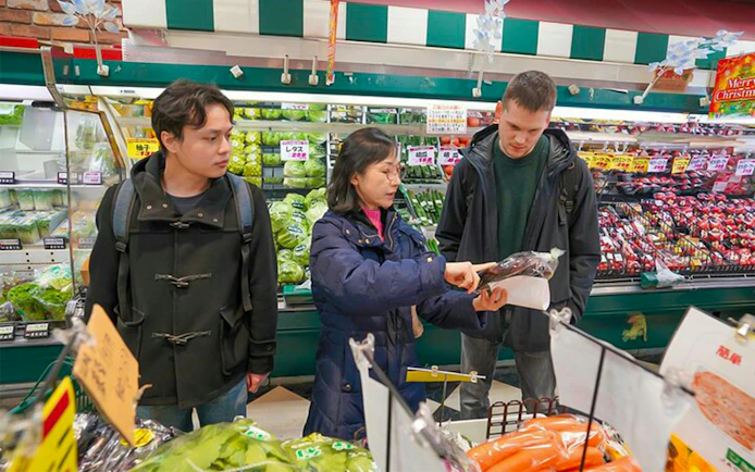 Shoppers selecting ingredients in a Tokyo supermarket for an izakaya-style cooking class.