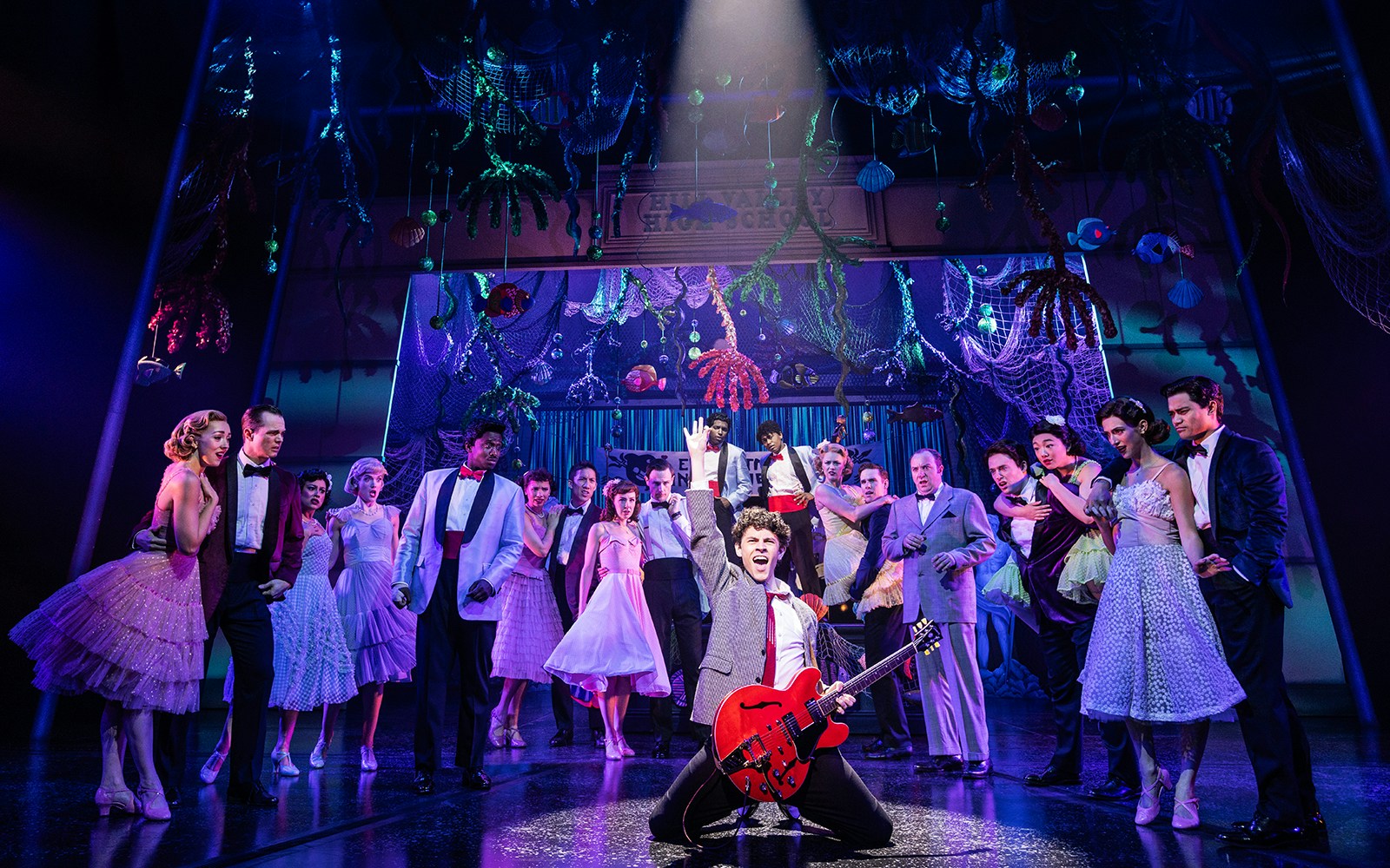 Cast performing a musical number in "Back to the Future the Musical" with vibrant stage decor.
