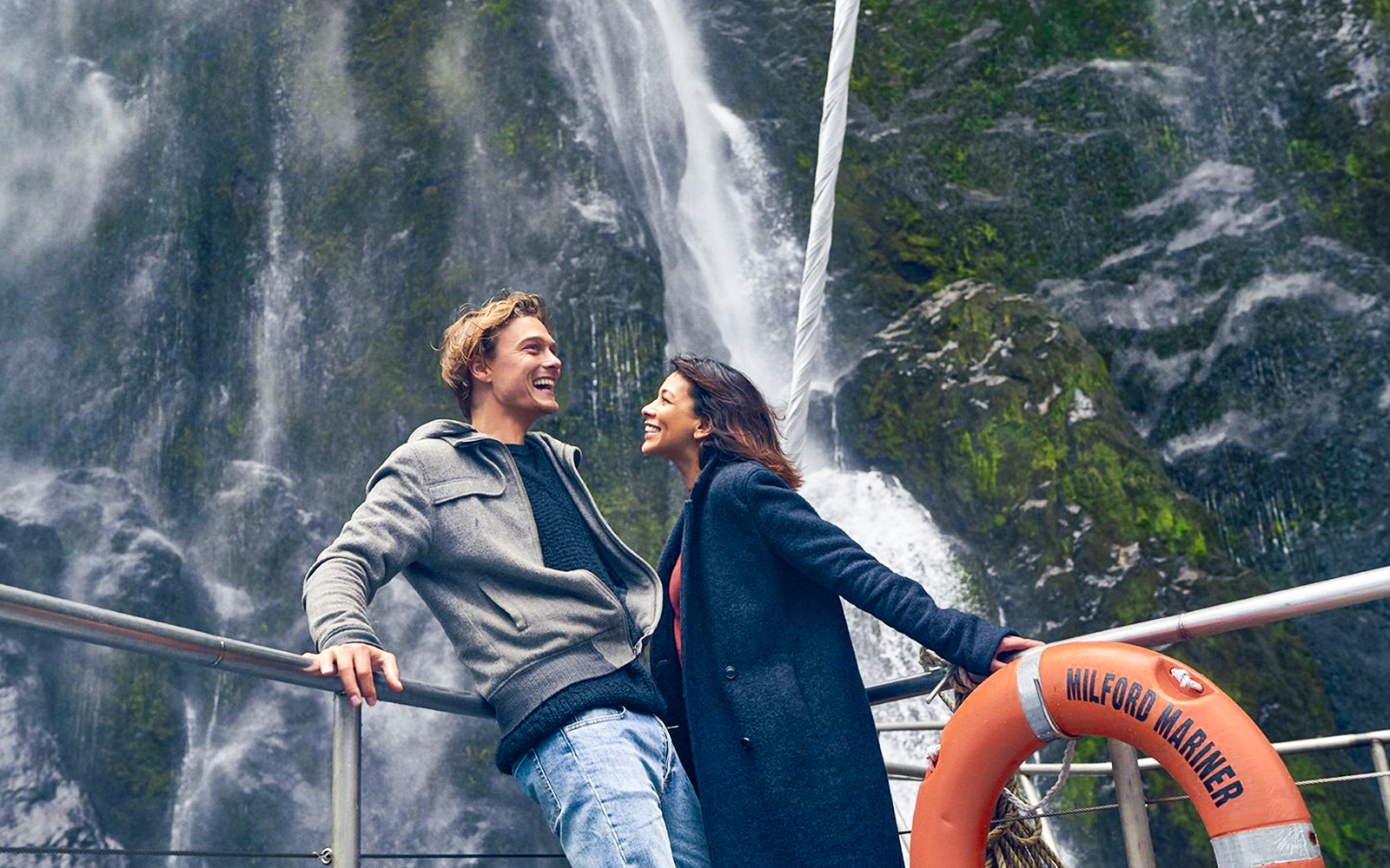 Couple enjoying Milford Sound waterfall view on cruise deck.