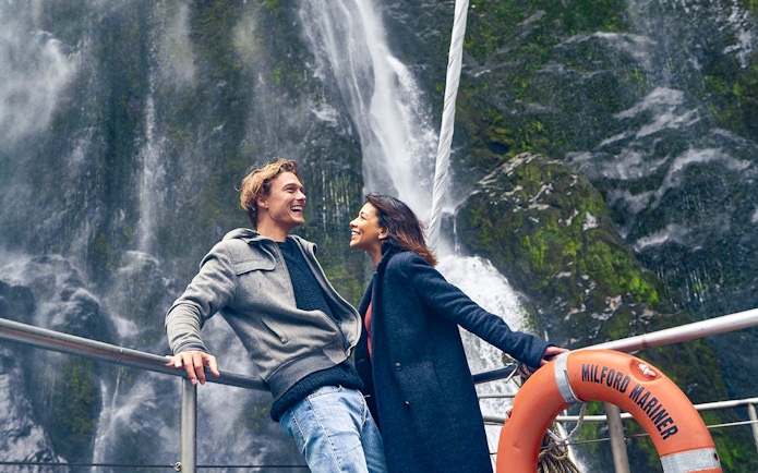 Couple enjoying Milford Sound waterfall view on cruise deck.