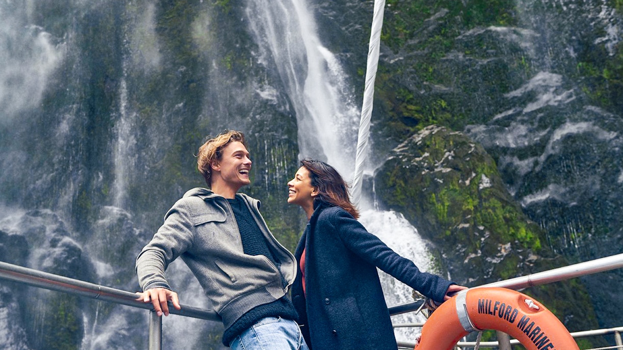 Couple enjoying Milford Sound waterfall view on cruise deck.