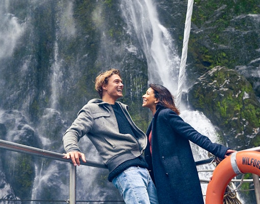 Couple enjoying Milford Sound waterfall view on cruise deck.