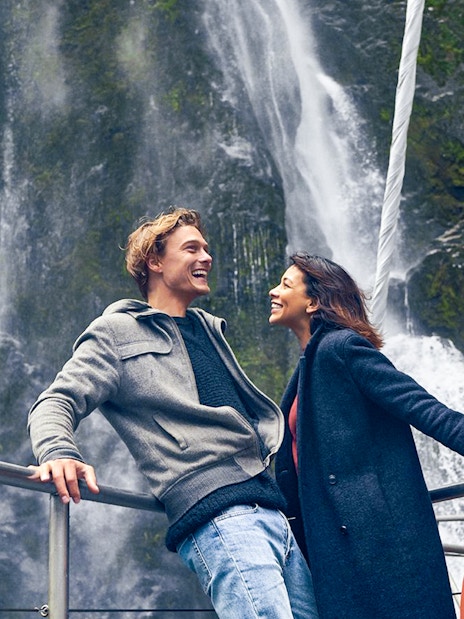 Couple enjoying Milford Sound waterfall view on cruise deck.