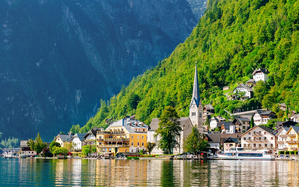 Hallstatt village with church spire and lake, surrounded by mountains, on a day trip from Vienna by bus.