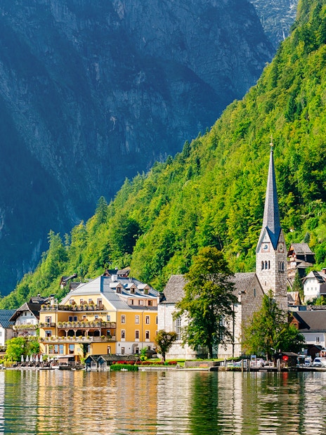 Hallstatt village with church spire and lake, surrounded by mountains, on a day trip from Vienna by bus.