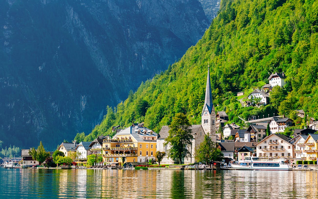 Hallstatt village with church spire and lake, surrounded by mountains, on a day trip from Vienna by bus.
