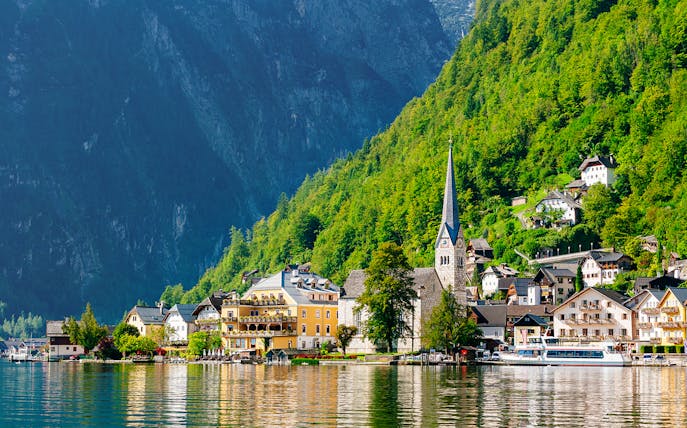 Hallstatt village with church spire and lake, surrounded by mountains, on a day trip from Vienna by bus.