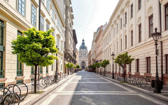 Zrínyi Street in Budapest leading to St. Stephen's Basilica, lined with trees and historic buildings.