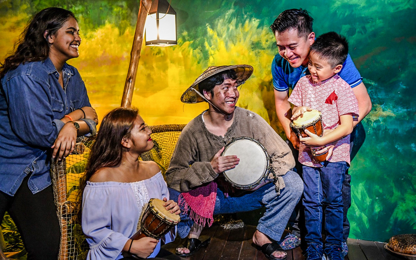 People engaging with a historical drumming exhibit at Madame Tussauds Singapore.