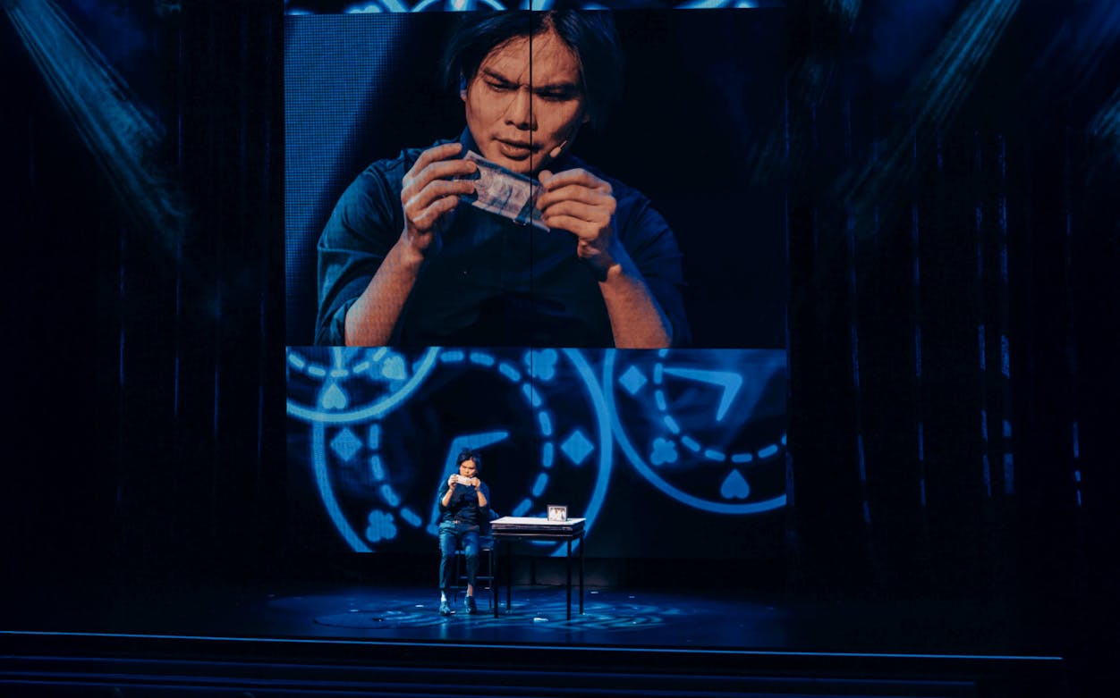 Magician performing card trick at Shim Lim show, Las Vegas stage.