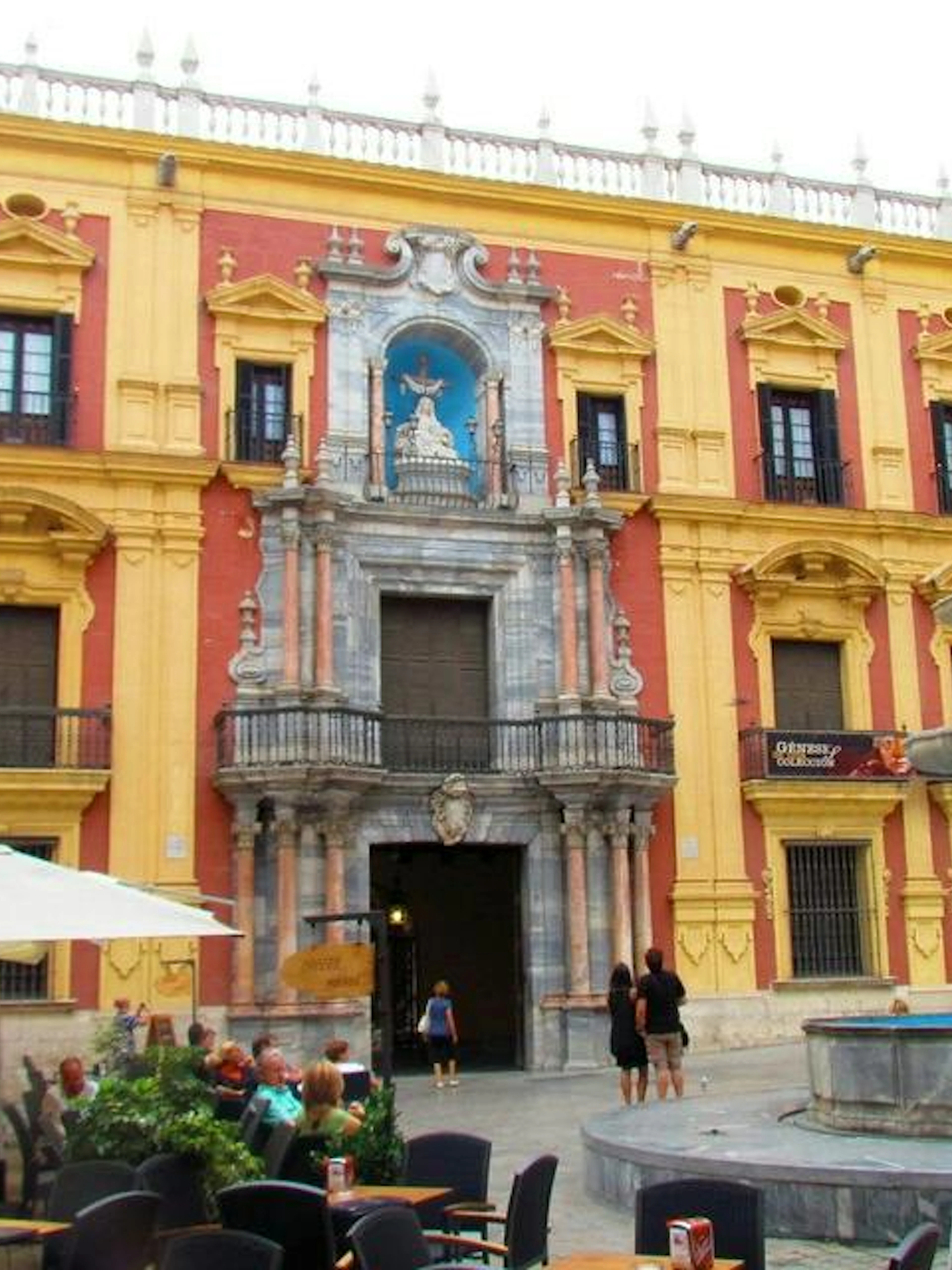 Facade of the Episcopal Palace in Malaga with a fountain in the foreground.