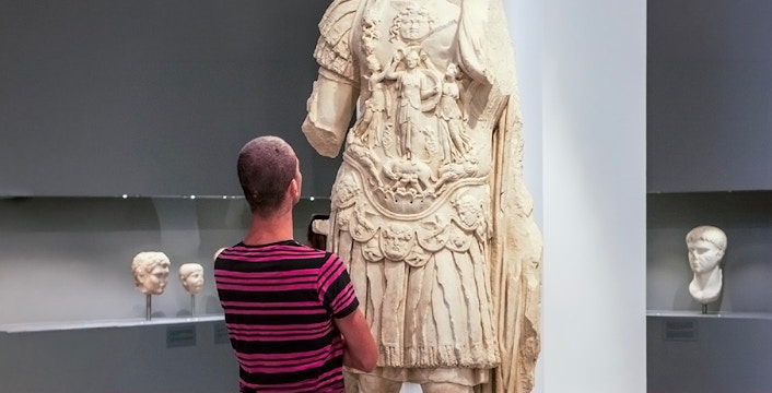 Tourist viewing ancient statue at Heraklion Archaeological Museum, Crete, Greece.