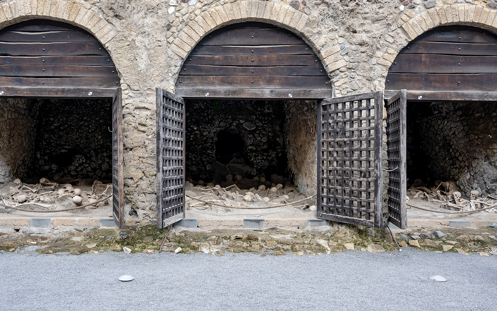 Skeletons of fugitives at Herculaneum entrance, Italy, in ancient stone chambers.