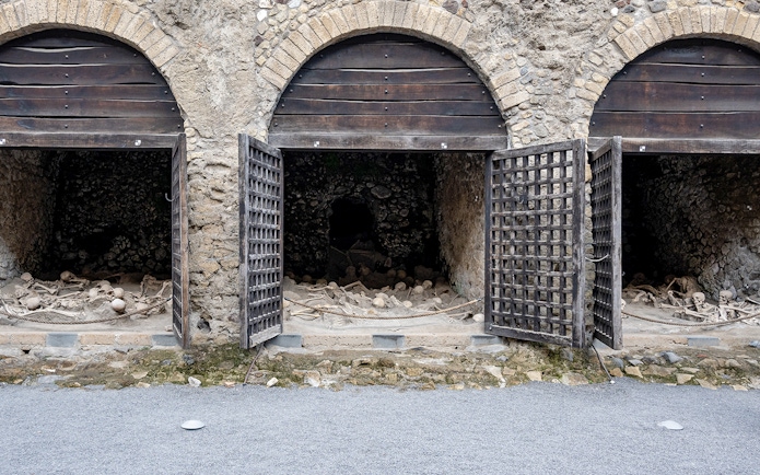 Skeletons of fugitives at Herculaneum entrance, Italy, in ancient stone chambers.