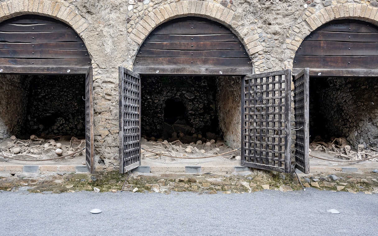Skeletons of fugitives at Herculaneum entrance, Italy, in ancient stone chambers.