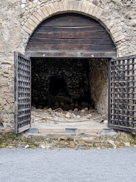 Skeletons of fugitives at Herculaneum entrance, Italy, in ancient stone chambers.