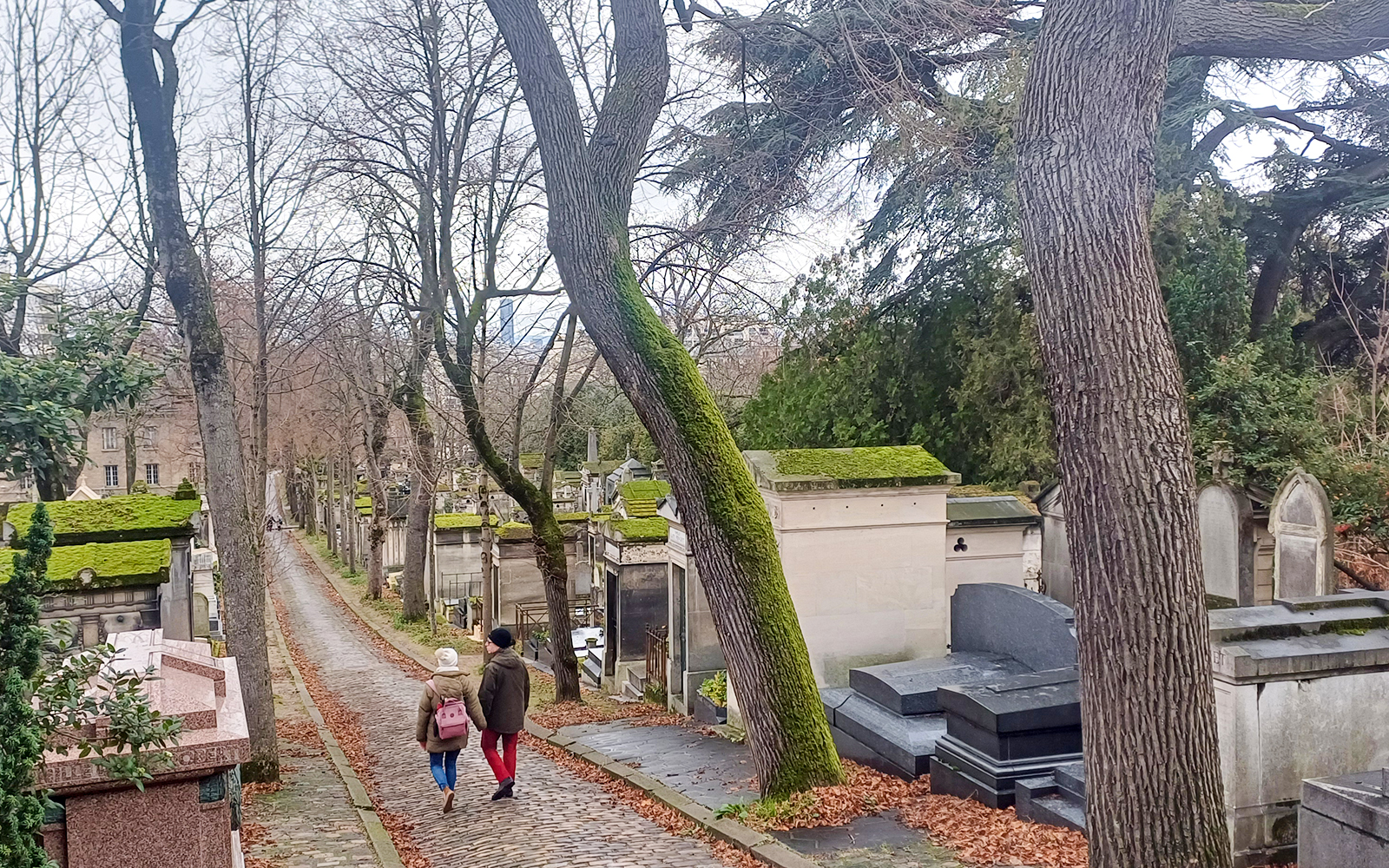 Visitors walking along a path in Père Lachaise Cemetery, Paris, France.