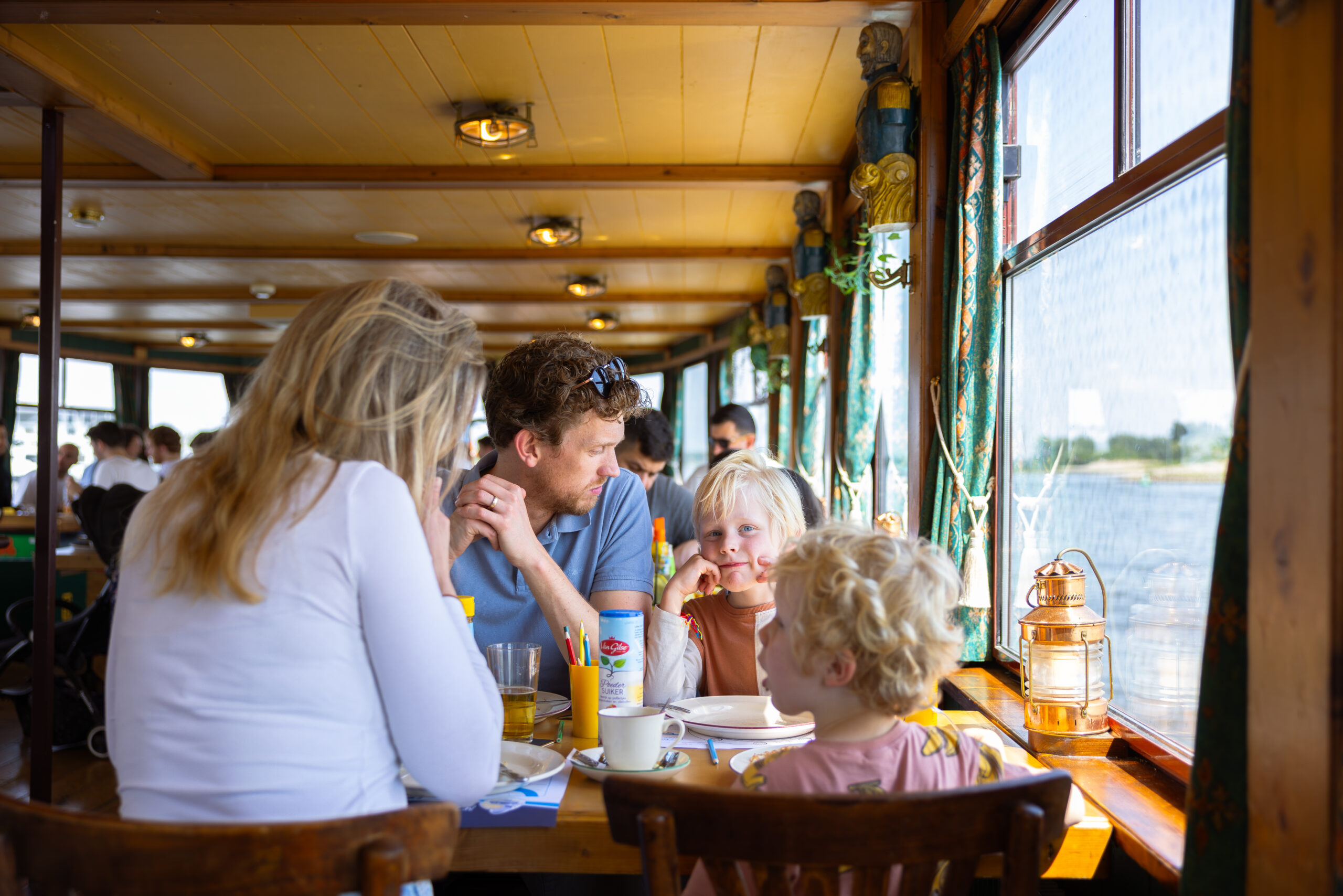 Guests enjoying a meal on the Pancake Cruise in Rotterdam with city skyline views.