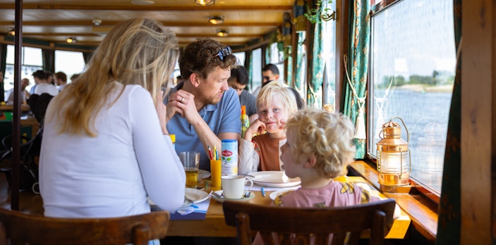 Guests enjoying a meal on the Pancake Cruise in Rotterdam with city skyline views.