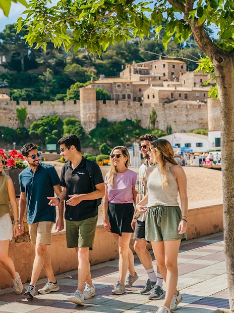 Tourists walking along the beach promenade near Tossa de Mar castle in Costa Brava.