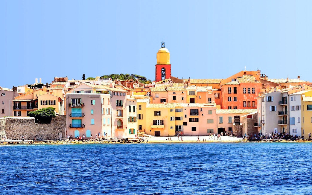 Colorful buildings and church tower along the waterfront in Saint Tropez, France.