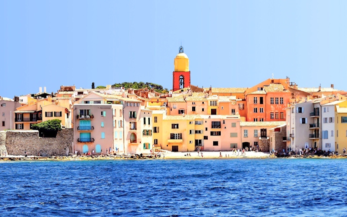 Colorful buildings and church tower along the waterfront in Saint Tropez, France.