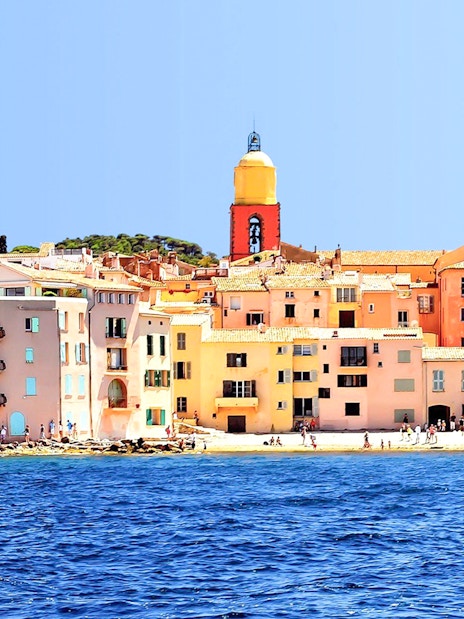 Colorful buildings and church tower along the waterfront in Saint Tropez, France.