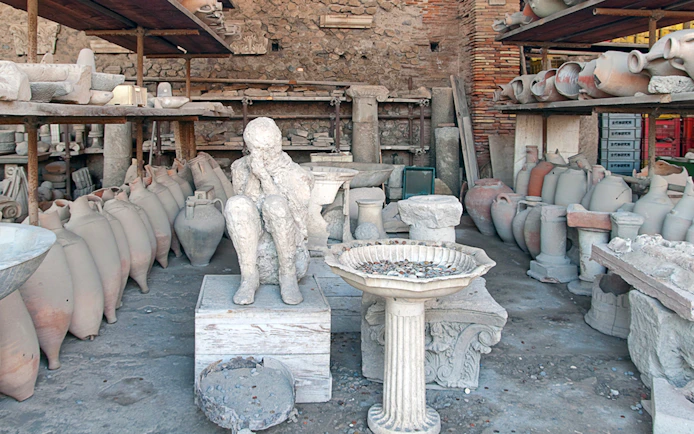 Plaster cast of a victim's body surrounded by ancient pottery in Pompeii.