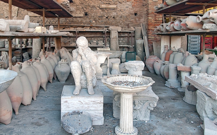 Plaster cast of a victim's body surrounded by ancient pottery in Pompeii.