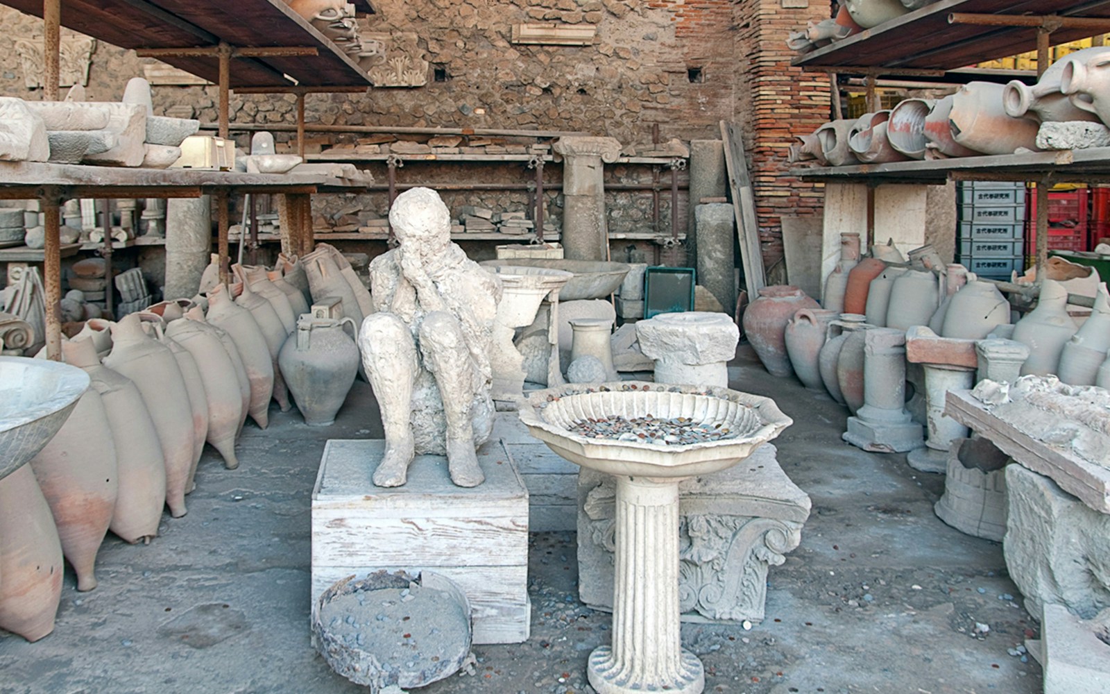 Plaster cast of a victim's body surrounded by ancient pottery in Pompeii.