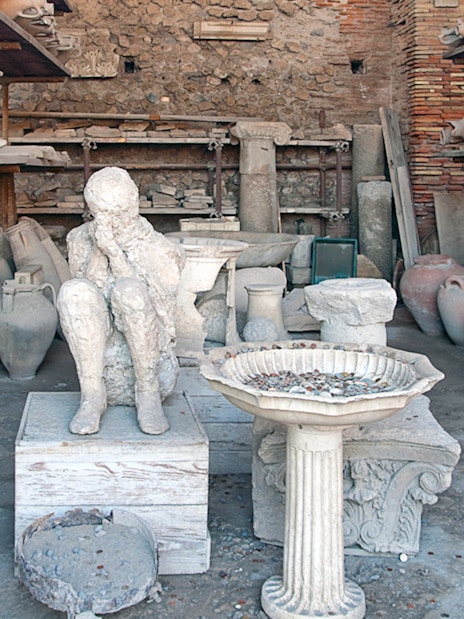 Plaster cast of a victim's body surrounded by ancient pottery in Pompeii.