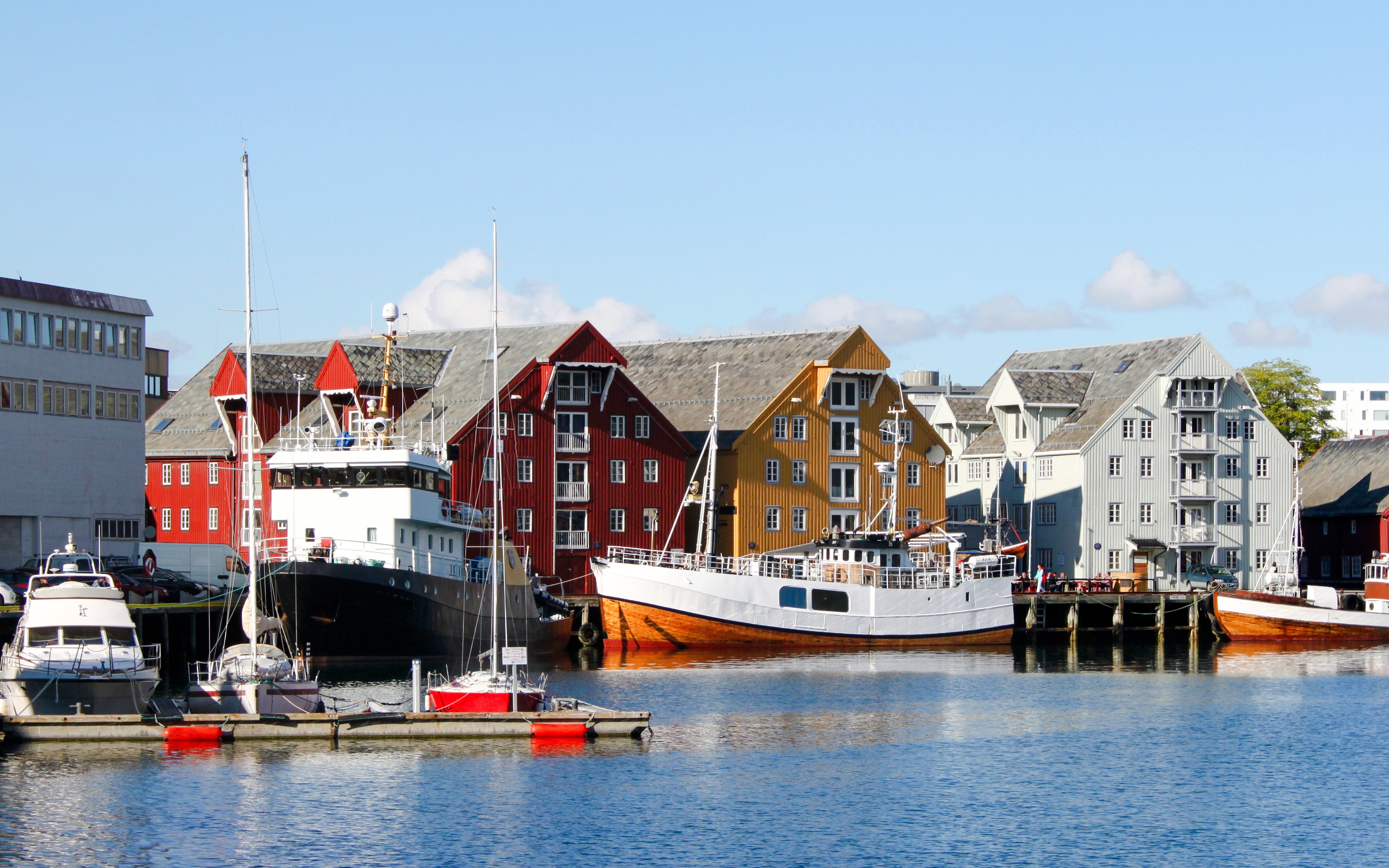 Colorful wooden buildings and boats in Tromso City Center harbor.