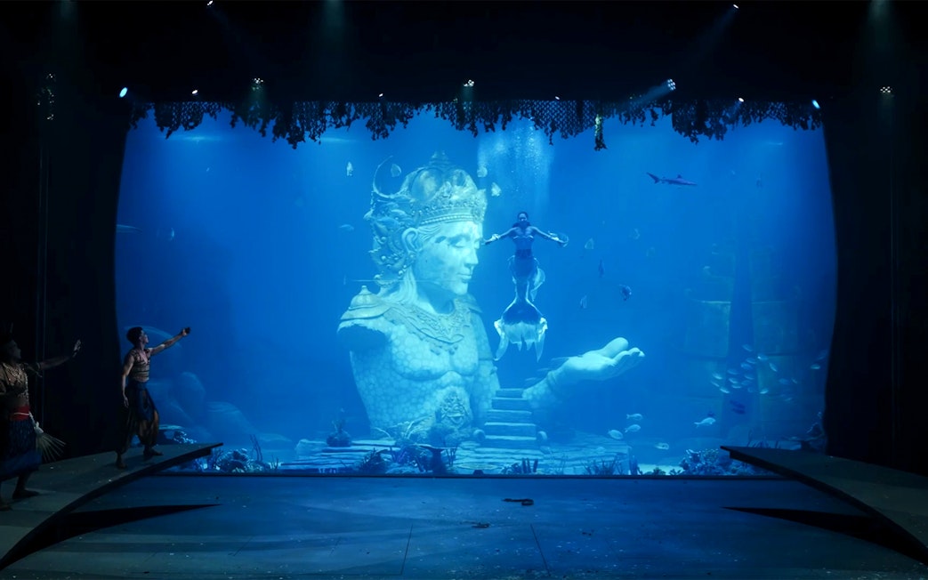 Underwater performance with mermaid near Varuna statue in theatrical dining experience.
