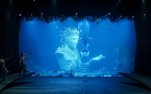 Underwater performance with mermaid near Varuna statue in theatrical dining experience.
