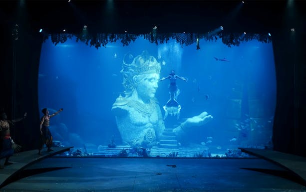 Underwater performance with mermaid near Varuna statue in theatrical dining experience.