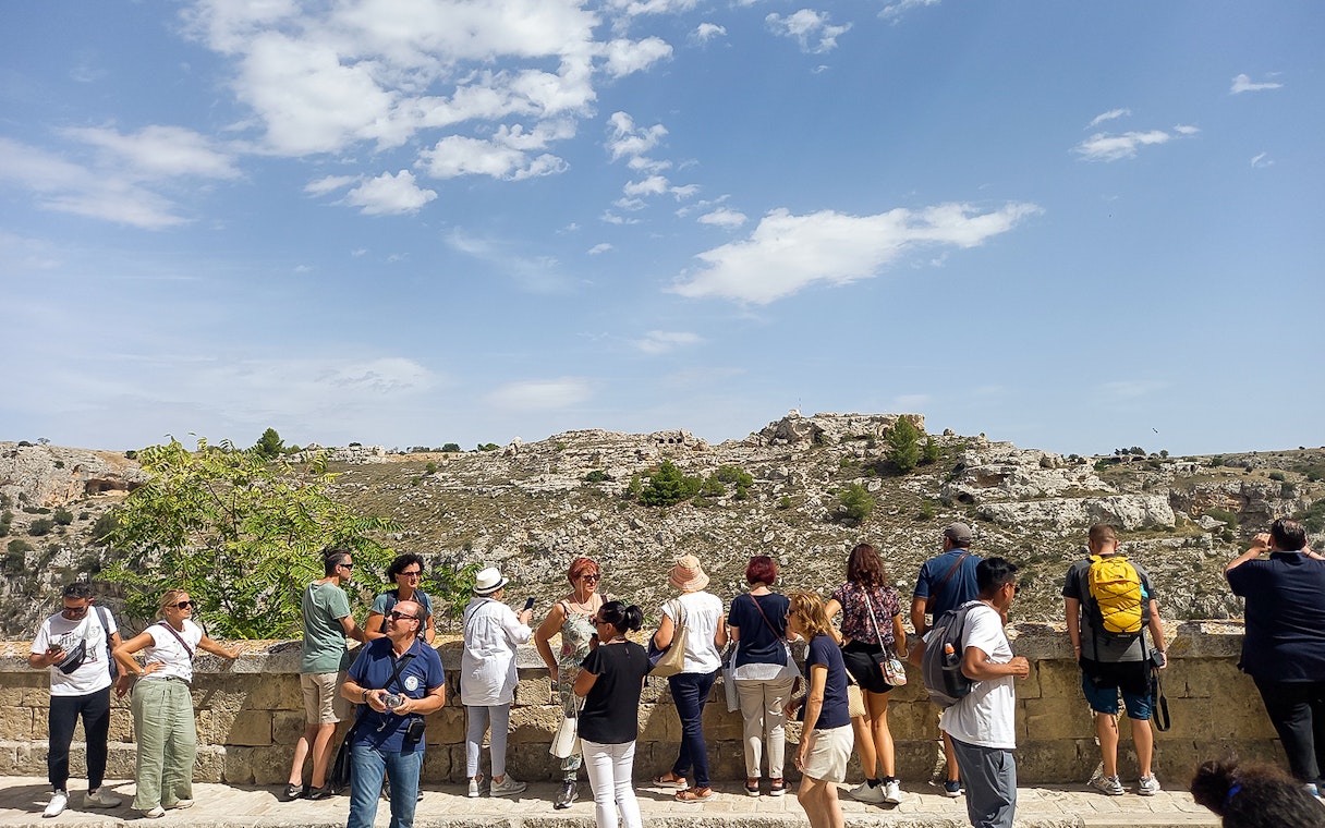 Tourists overlooking the rocky landscape of Matera during a bus tour with audio guide.