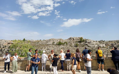Tourists overlooking the rocky landscape of Matera during a bus tour with audio guide.
