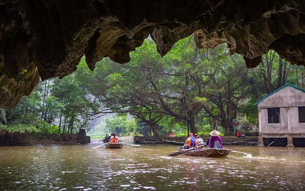 Boat tour through Tam Coc caves with lush greenery and limestone formations, near Hanoi.