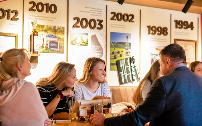 Visitors enjoying a tasting session at the Slivovitz Museum with historical displays in the background.