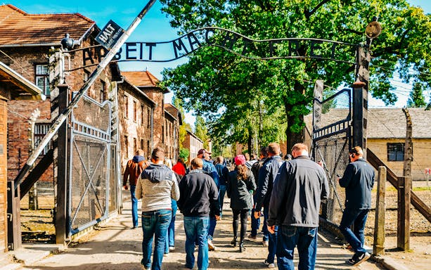 Visitors entering Auschwitz-Birkenau gate during guided tour, Poland.