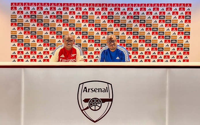 Arsenal FC Emirates Stadium press room with two people seated at the desk.