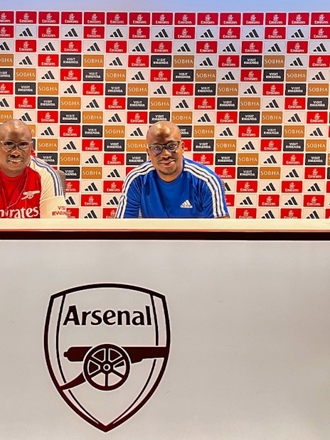 Arsenal FC Emirates Stadium press room with two people seated at the desk.